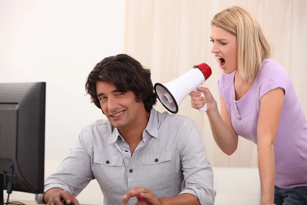 Чоловік робить комп'ютер і жінка кричить на нього з мегафоном — стокове фото