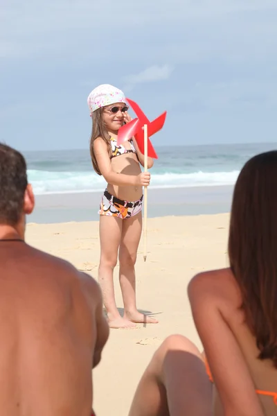 Chica con un molino de viento en una playa —  Fotos de Stock