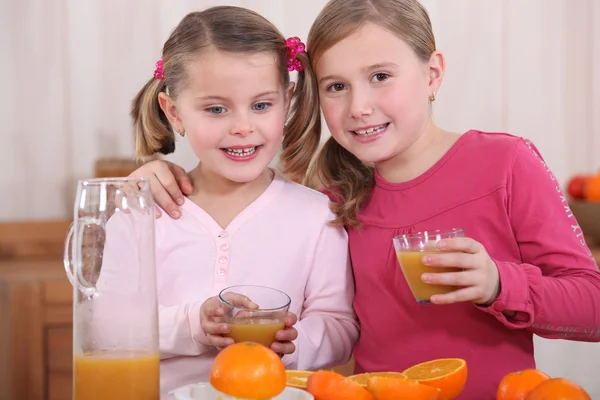 Маленькие девочки сжимают апельсины — стоковое фото