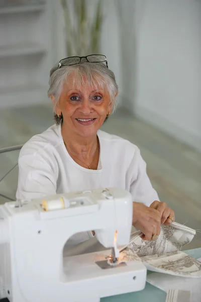Oudere dame met behulp van naaimachine — Stockfoto