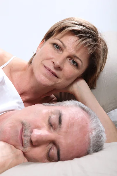 Kvinna ligga bredvid sin sovande make — Stockfoto