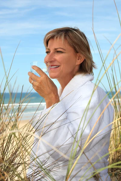 Mulher bebendo um copo de água em uma duna de areia — Fotografia de Stock
