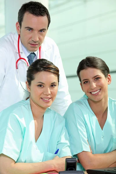 Doctor standing with two nurses at a nursing station — Stock Photo, Image