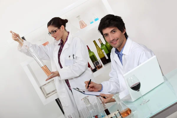Vrouwelijke en mannelijke wijn laboratorium technici — Stockfoto