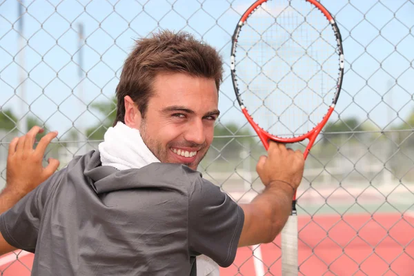 Lächelnder männlicher Tennisspieler steht vor einem städtischen Gericht — Stockfoto