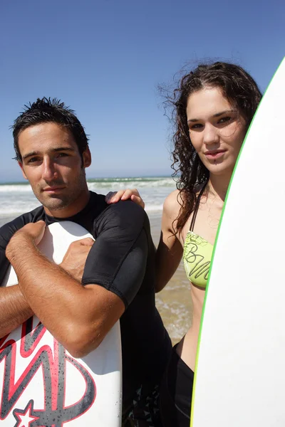Jovem casal surfista ficou na praia com suas pranchas de surf — Fotografia de Stock
