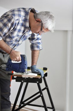 Senior carpenter sawing plank of wood clipart