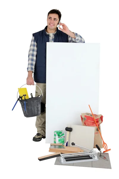 Tile cutter stood holding bucket next to blank panel — Stock Photo, Image