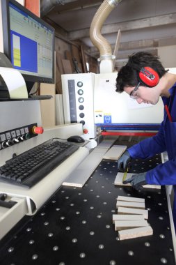 Young apprentice measuring a piece of wood clipart