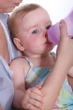 Baby drinking water from a bottle clipart