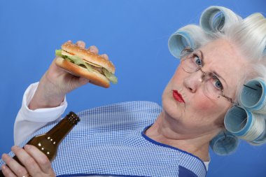 An old lady enjoying a burger and a beer. clipart