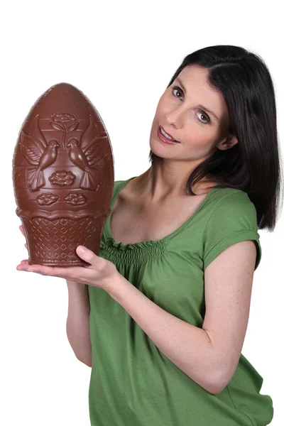 Jeune femme portant un gros oeuf de Pâques en chocolat — Photo