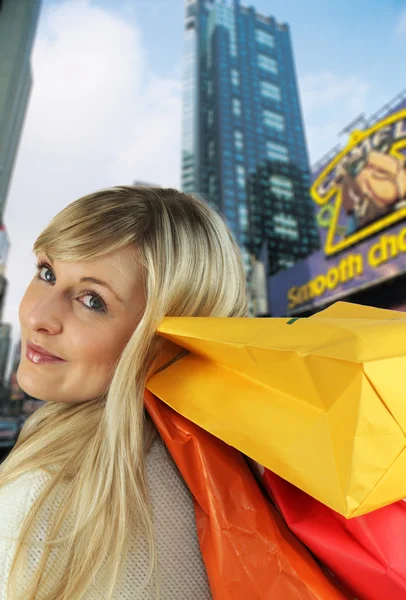 Blonde uitvoering van boodschappentassen op schouder — Stockfoto
