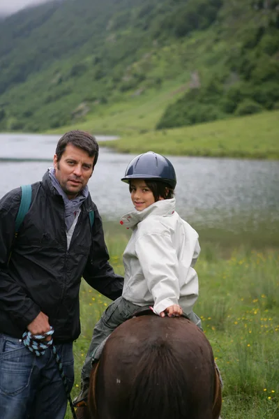 Чоловік навчає дитину їздити на коні — стокове фото