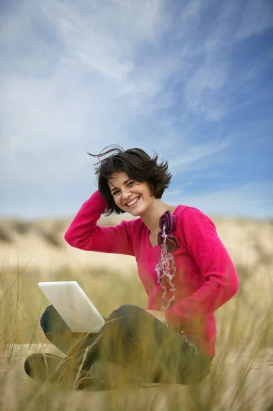 Brunett med laptop på stranden — Stockfoto