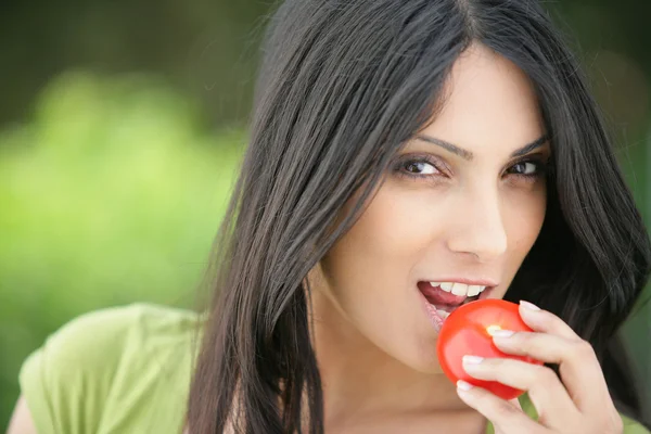 Bruneta kousání do šťavnaté červené jablko — Stock fotografie