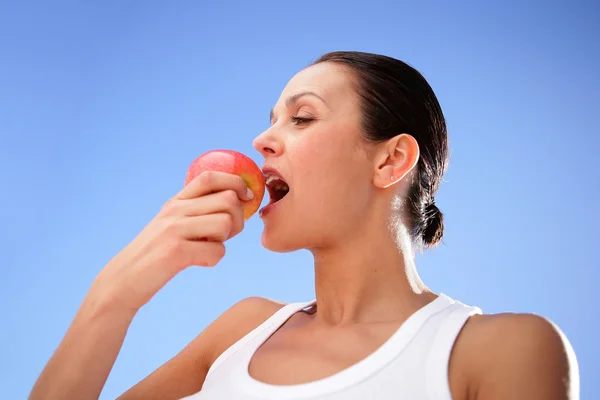 Brunette biting into tasty apple — Stock Photo, Image