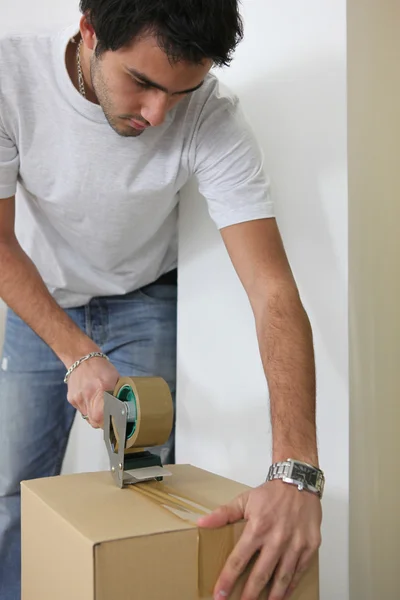 Young man wrapping cardboard — Stockfoto