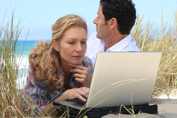 Wife working on laptop on the beach. — Stock Photo, Image