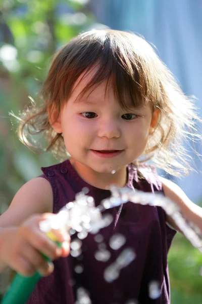 Kleinkind spielt mit Gartenschlauch — Stockfoto