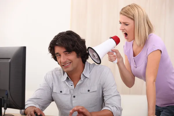 Un hombre haciendo computadoras y una mujer gritándole con un megáfono —  Fotos de Stock