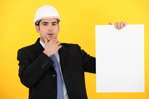 Businessman in a hardhat with a board left blank for your message — Stock Photo, Image
