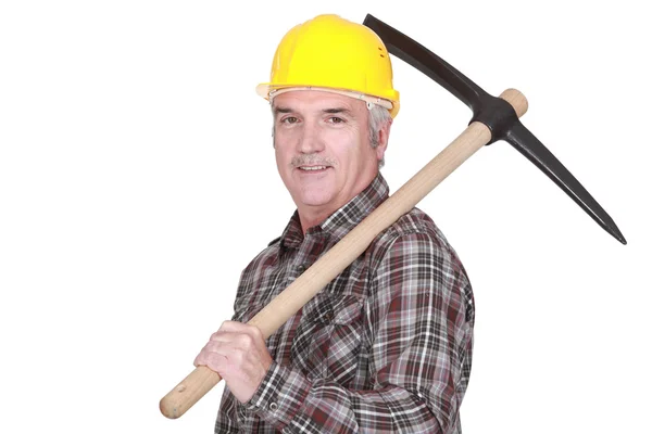 Mature laborer carrying a pickaxe on his shoulder — Stock Photo, Image