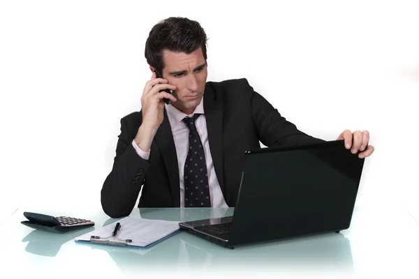 Empresário fazendo chamada enquanto lia a partir da tela do computador — Fotografia de Stock