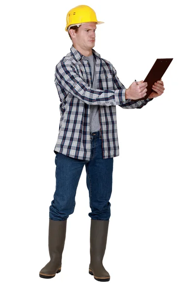 Incredulous tradesman looking at a clipboard — Stock Photo, Image