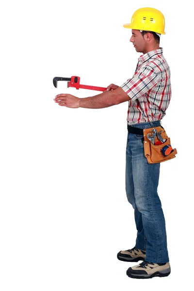 Comerciante usando una llave de tubo para ayudar a arrastrar y colocar un objeto —  Fotos de Stock