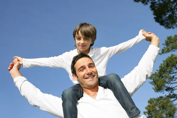 Kleine jongen rijden op zijn vaders schouders — Stockfoto