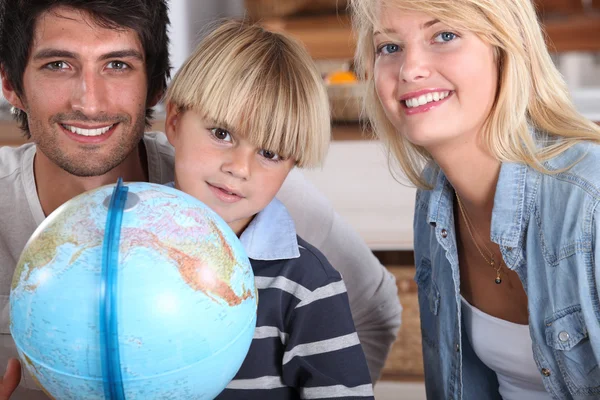 Een kleine jongen en zijn ouders in de buurt van een wereldbol glimlachen — Stockfoto
