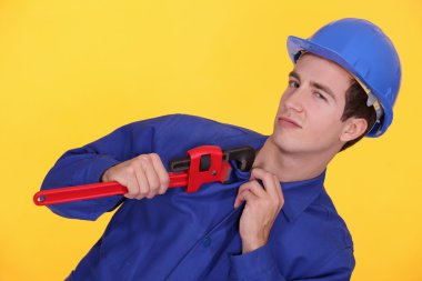 Tradesman's uniform stuck in the jaw of a pipe wrench clipart