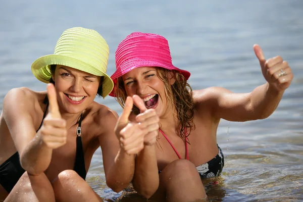Duas mulheres na praia dando o polegar para cima — Fotografia de Stock