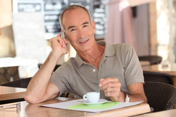 Senior having an expresso while talking on his cellphone — Stock Photo, Image