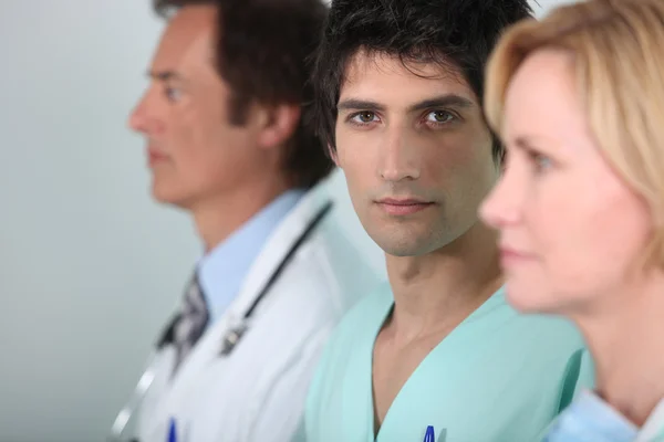 Jeune homme en blouse avec d'autres membres du personnel médical — Photo