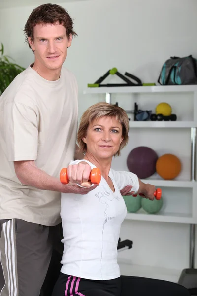 Personlig træner hjælper sin klient med hendes kropsholdning - Stock-foto