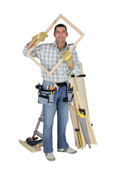 Carpintero sosteniendo marco de madera — Foto de Stock
