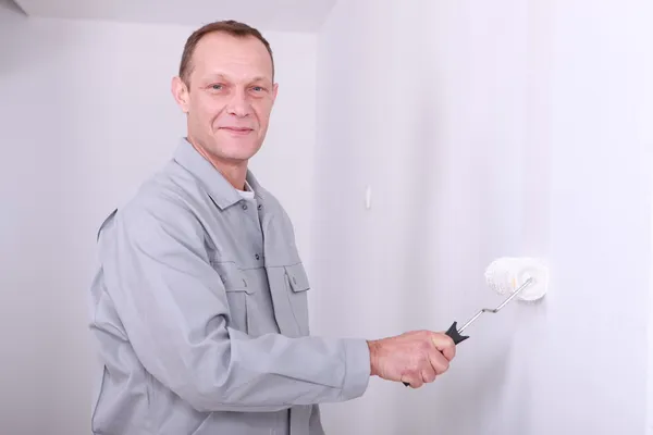 Чоловік в комбінезоні малює кімнату білою — стокове фото