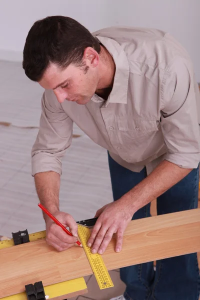 Hombre midiendo tablón de madera —  Fotos de Stock