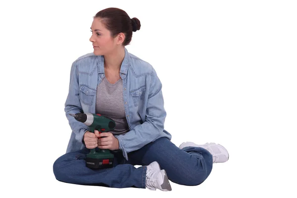 Женщина сидела на полу с дрелью — стоковое фото