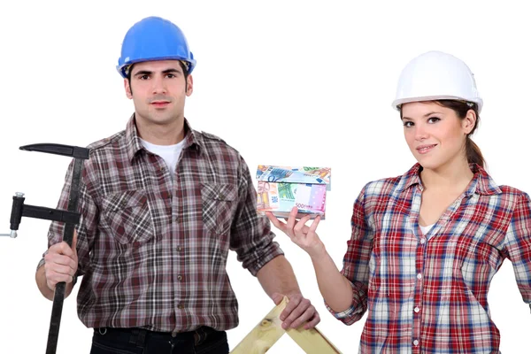 A team of tradespeople holding their tools and a house model — Stock Photo, Image