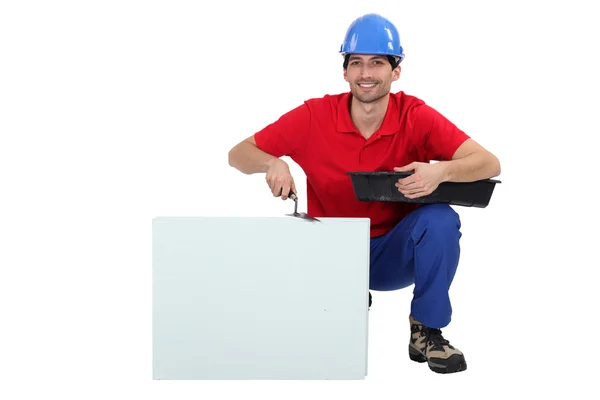 Tradesman inginocchiato accanto a un cartello vuoto — Foto Stock
