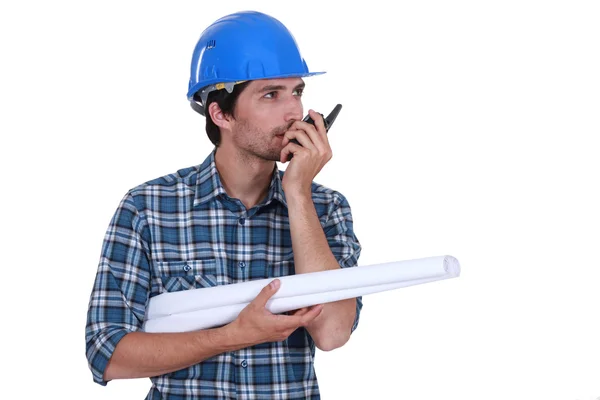 Engenheiro com planos e um walkie talkie — Fotografia de Stock