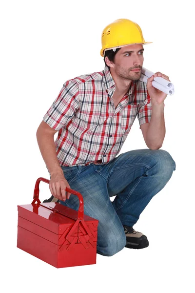 Trabalhador ajoelhado por seu kit de ferramentas — Fotografia de Stock