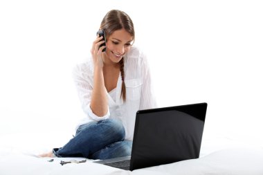 Woman talking on the phone and looking at her laptop clipart