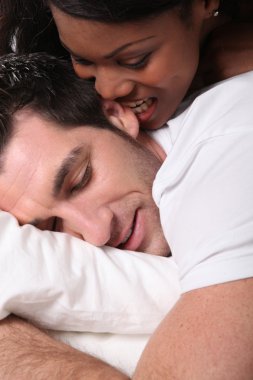 Woman biting her husband's ear in bed clipart
