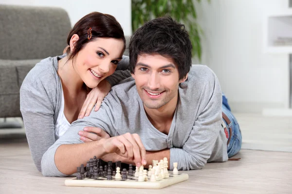 Casal deitado no chão jogando xadrez — Fotografia de Stock