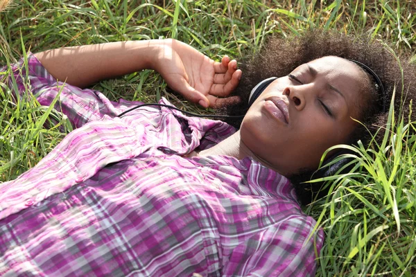 Mulher deitada no campo ouvindo música — Fotografia de Stock