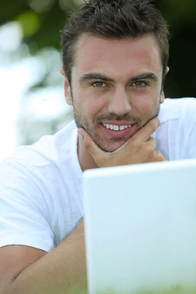 Człowiek głaszcząc jego podbródek i patrząc na jego laptopie — Zdjęcie stockowe